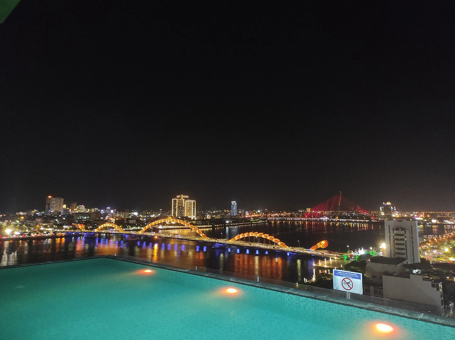Dragon Bridge at night from a rooftop pool